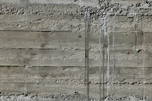 Concrete wall with wooden pattern impress from wooden form board shuttering and with sags of cement