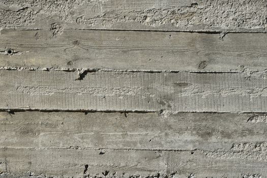 Concrete wall with wooden pattern impress from wooden form board shuttering and with sags of cement