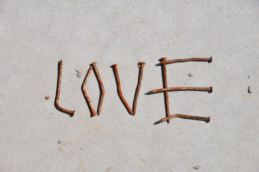 LOVE word formed by rusty nails at grey concrete background