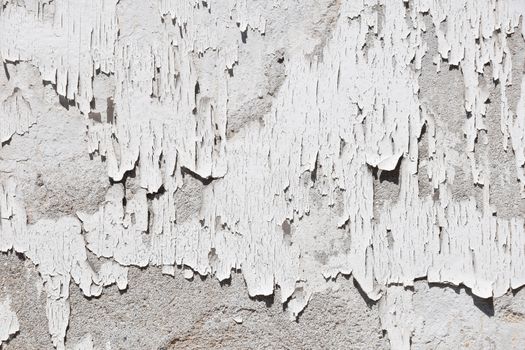 Vintage flakes of old white paint on grey concrete wall