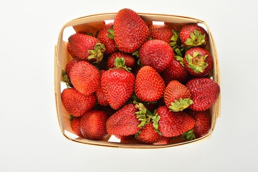 Mellow fresh summer strawberries in wooden basket isolated on white background, top view