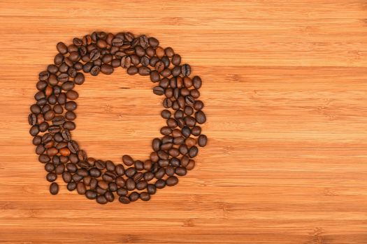 Circle shaped coffee beans of Roasted Arabica espresso beans frame over wooden bamboo board background