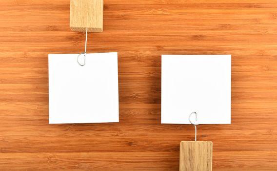 Opposite Opinions - Two white paper notes with wooden holders in different directions on bamboo wooden background for presentation