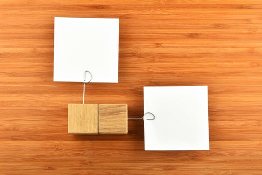 Different Opinion - Two white paper notes with wooden holders in different directions on wooden bamboo background for presentation