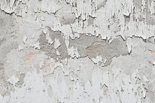 Vintage flakes of old white paint over grey concrete wall