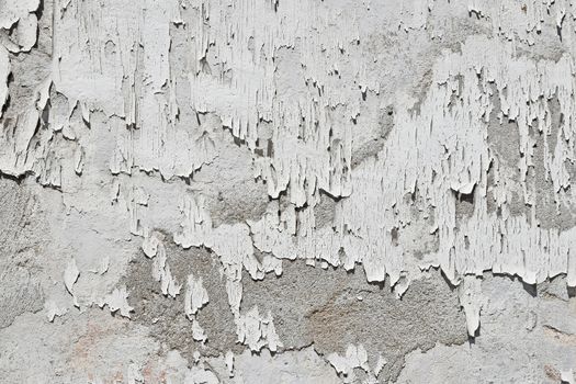Vintage flakes of old white paint over grey concrete wall