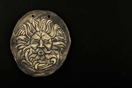 Tourist ceramic souvenir replica of male Gorgon Medusa head in Minerva temple in Roman Bath in England isolated on black