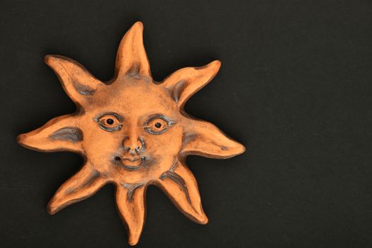 Smiling glazed ceramic sun happy face souvenir isolated on black