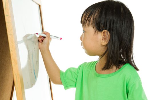 Happy cute Asian Chinese toddler girl drawing or writting with marker pen on a blank whiteboard at home, preschool, daycare or kindergarten in plain white isolated background.