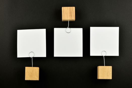 Opposite Opinion - three white paper notes with wooden holders in different directions isolated on black paper background for presentation