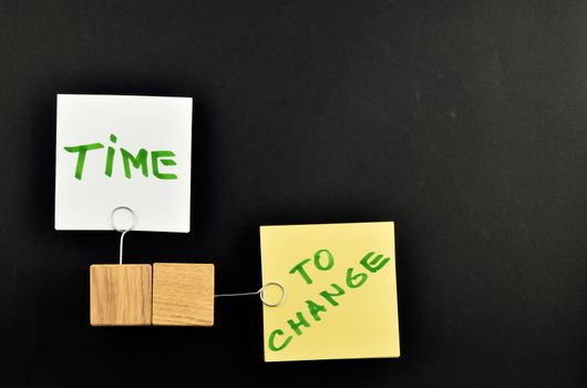 Time to change,  Two paper notes, white & yellow,  with wooden holders in different directions isolated on black paper background for presentation