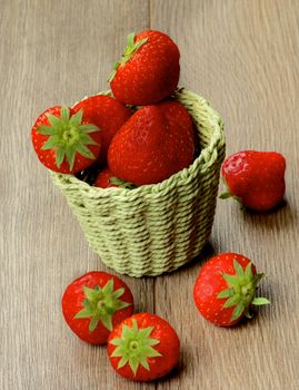 Fresh Ripe Strawberries in Green Wicker Basket closeup on Textured Wooden background