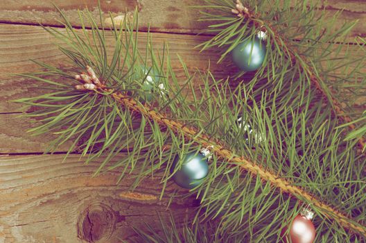 Christmas Decoration with Blue and Pink Baubles on Fluffy Green Pine Branch closeup on Rustic Wooden background. Retro Styled
