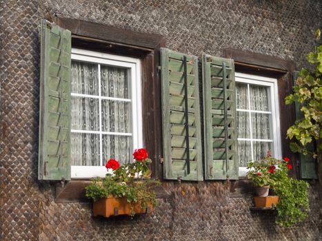 Traditional Window of Swiss wooden house with flower pot.