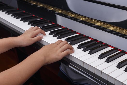 Boys hands play on piano keys.