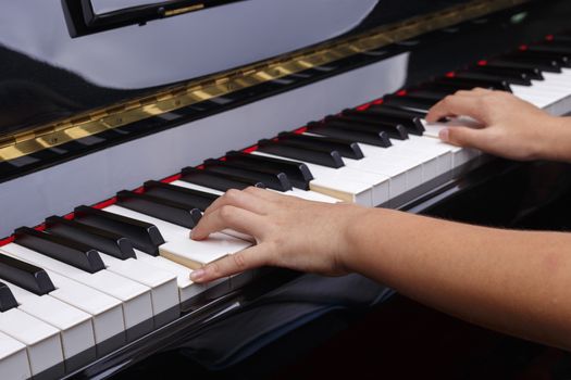 Boys hands play on piano keys.