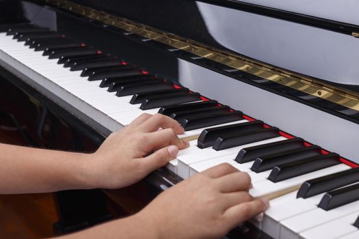 Boys hands play on piano keys.