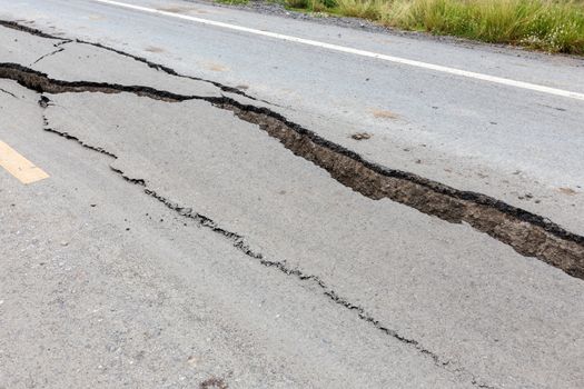 Cracked and broken asphalt road from earthquake.