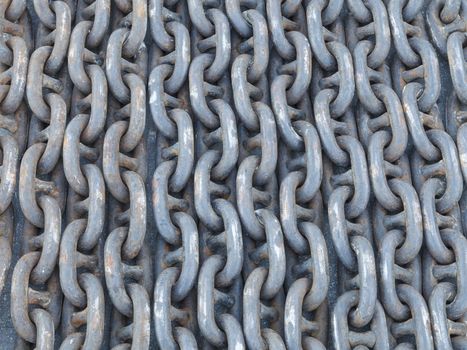 Many lines of used rusty heavy iron chain on the ground.