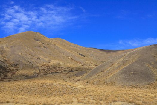 Colorful countryside of dried grassland valley near Lindis Pass, South Island, New Zealand.
