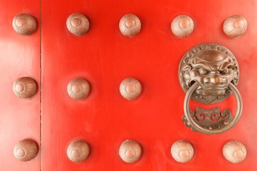 Chinese lion face door knob on the red gate of buddhist temple in Singapore.