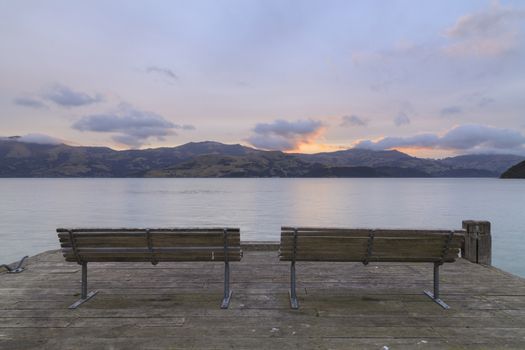 A pair of Benches at Wooden pier after sunset in Akaroa, Canterbury region, South Island, New Zealand.