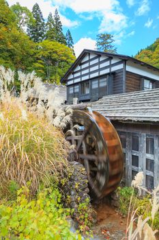 Old Japanese farmhouse with water mill in autumn.