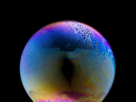 Close up of a colorful Shampoo Bubble over black background look like strange planet in universe.