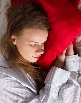 Beautiful woman is sleeping on red pillow. Pretty girl on the couch.