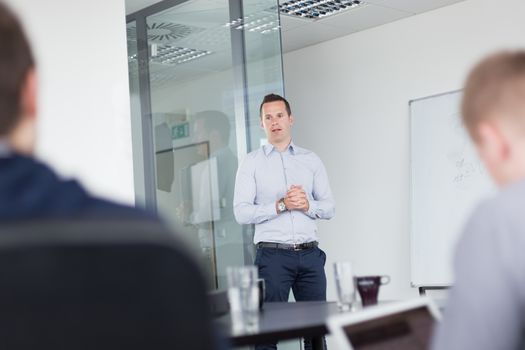 Business man making a presentation at office. Business executive delivering a presentation to his colleagues during meeting or in-house business training, explaining business plans to his employees.