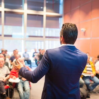 Speaker at Business Conference with Public Presentations. Audience at the conference hall. Entrepreneurship club. Rear view. Horisontal composition. Background blur.