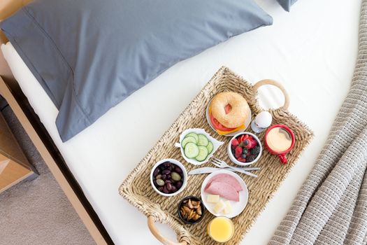 High Angle View of Wicker Breakfast Tray on Unmade Bed in Hotel Room