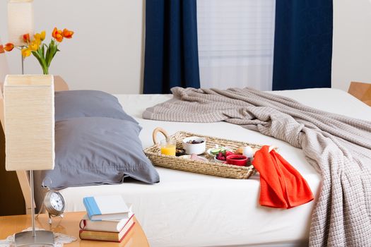 Breakfast Tray Filled with Variety of Foods Sitting on Unmade Bed in Tastefully Decorated Bedroom