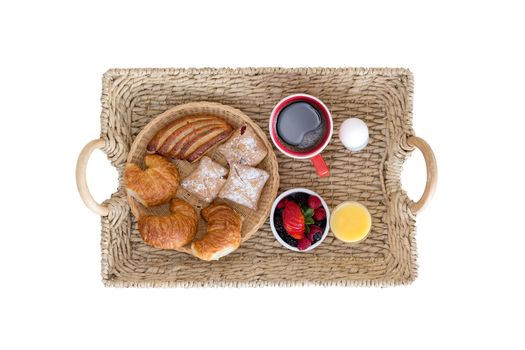 High Angle View of Wicker Breakfast Tray with Assortment of Breads and Berries, Coffee, Juice and Hard Boiled Egg on White Background