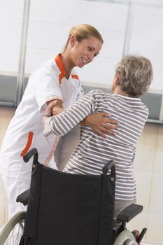 Careful female caregiver helping senior woman to stand up