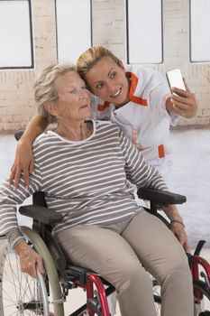 Young nurse taking a selfie to ensure the family about the good condition of the grandmother.