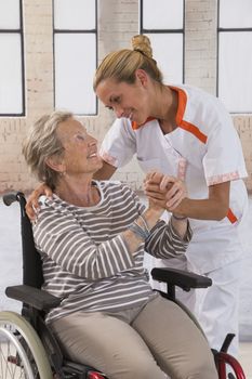 Health care nurse holding elderly lady's hand with caring attitude
