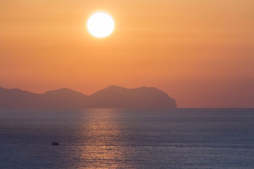 Sunset at sea with shipping boat silhouette.