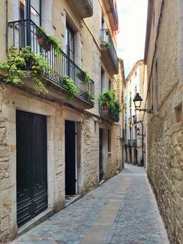 Narrow street with stone buildings in Girona. Catalonia, Spain.