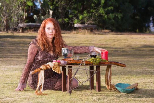 Caucasian priestess in outdoor pagan ritual with altar