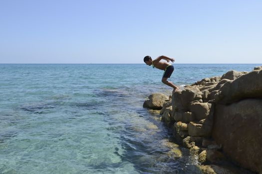 Carefree summer for the boy who dives from the rocks into the sea.