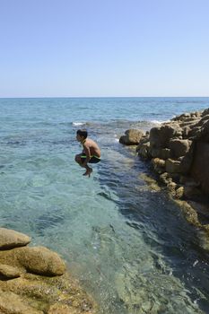 Carefree summer for the boy who dives from the rocks into the sea.