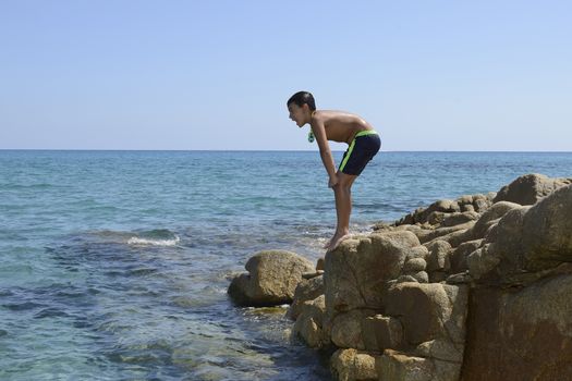 Carefree summer for the boy who dives from the rocks into the sea.