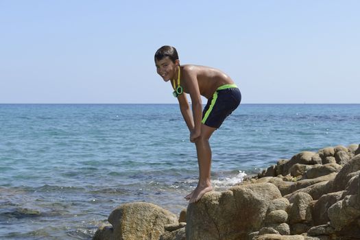 Carefree summer for the boy who dives from the rocks into the sea.