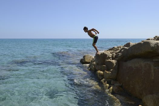 Carefree summer for the boy who dives from the rocks into the sea.