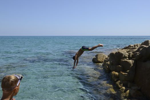 Carefree summer for the boy who dives from the rocks into the sea.