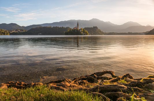 Little Island with Catholic Church in Bled Lake, Slovenia  at Sunrise with Castle and Mountains in Background