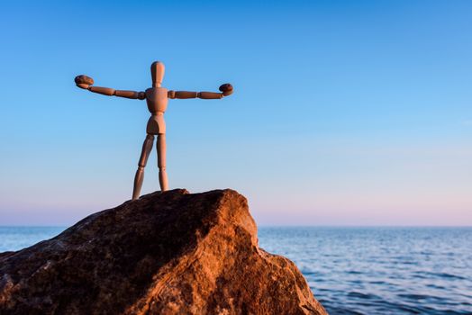 Wooden mannequin on the top of boulder