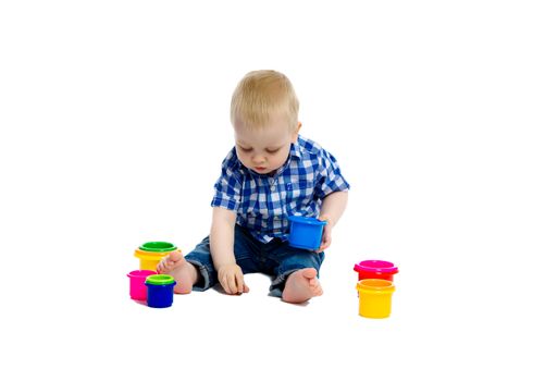 A little boy in checkered shirt plays on the floor. White background. Studio