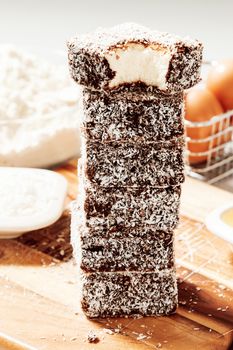 Group of Lamingtons on a timber metal baking tray with food ingredients in the background